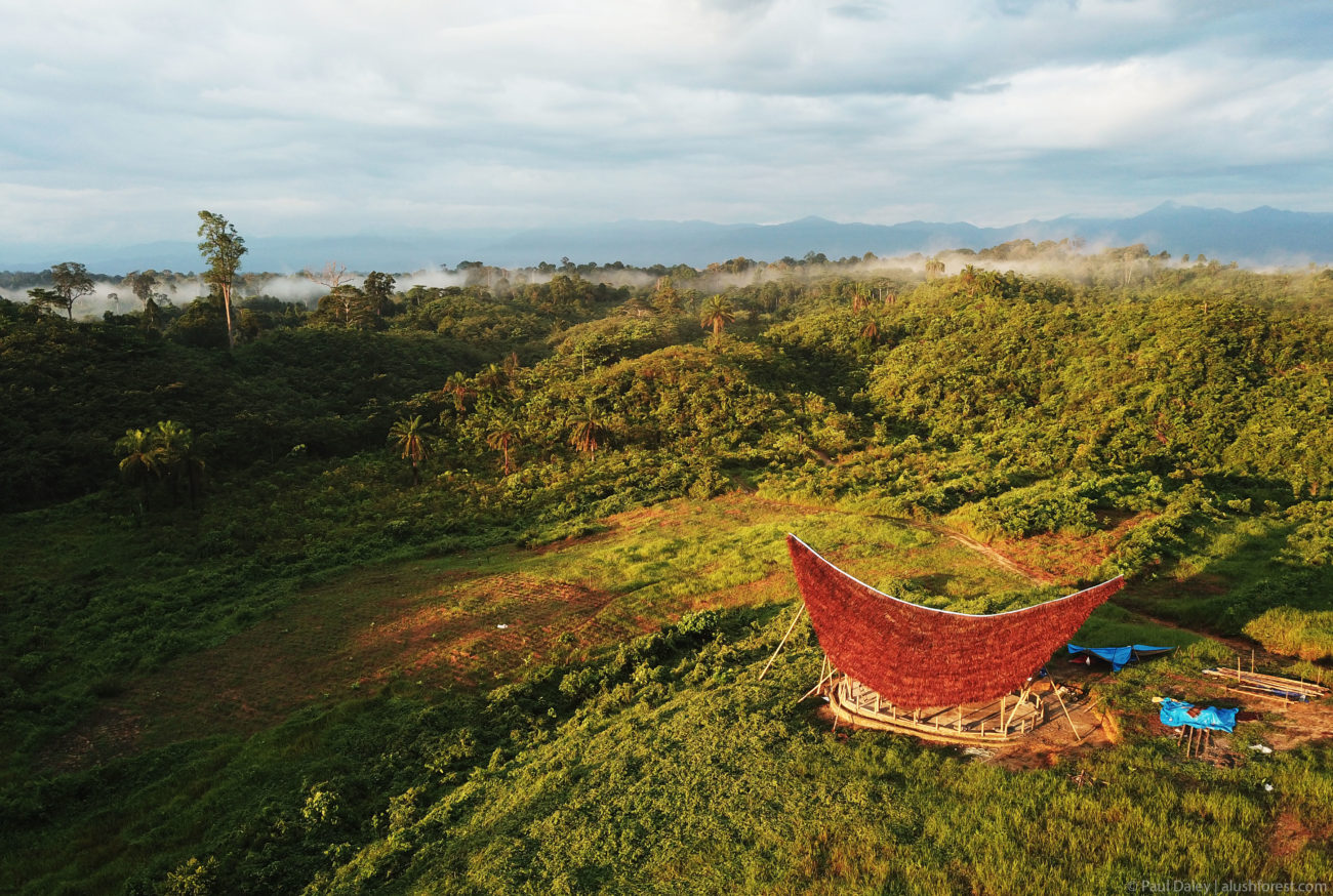 An aerial view of a bamboo building in a green landscape