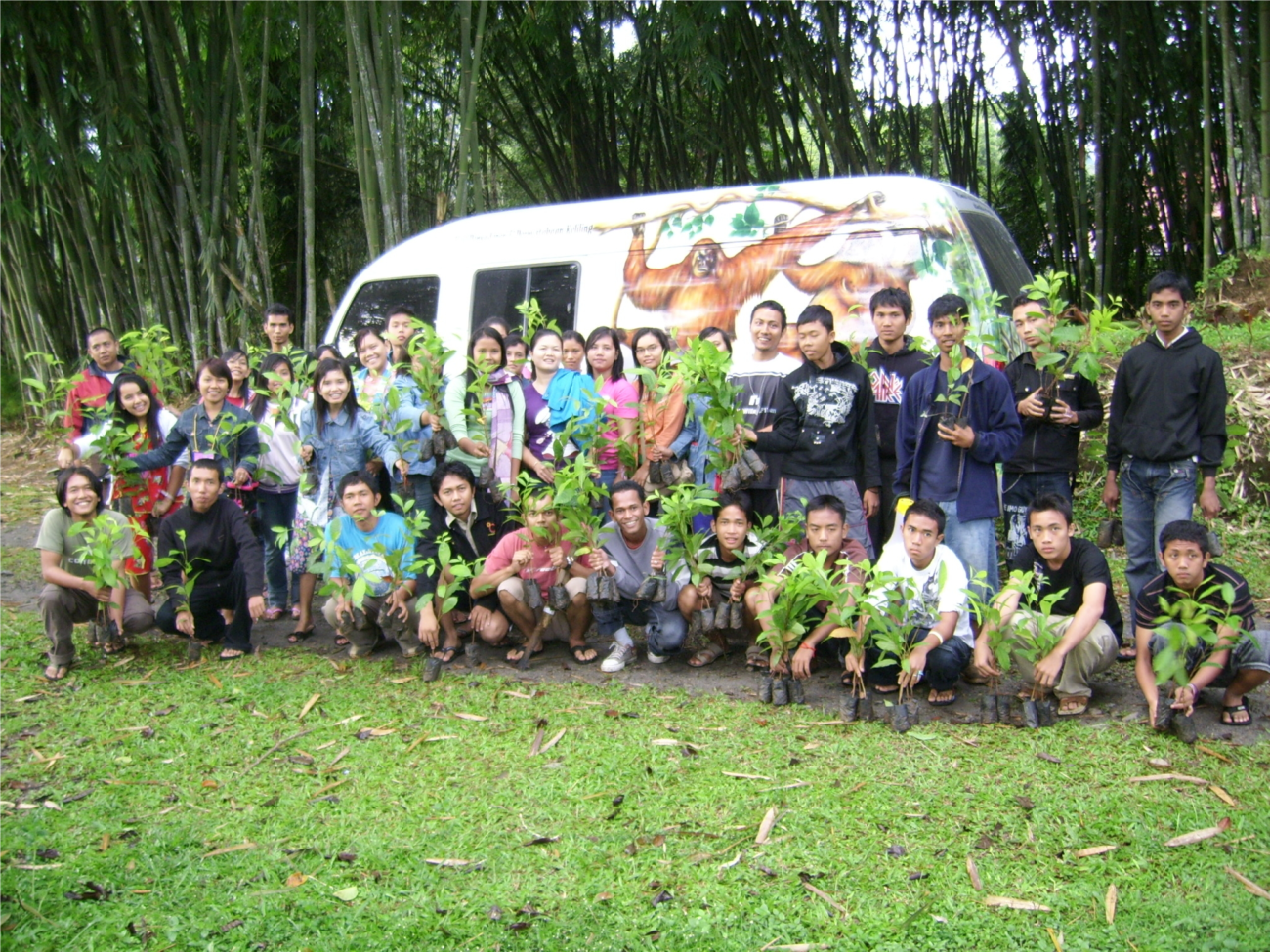 A group of people standing in front of an environmental education van with orangutans painted on it.