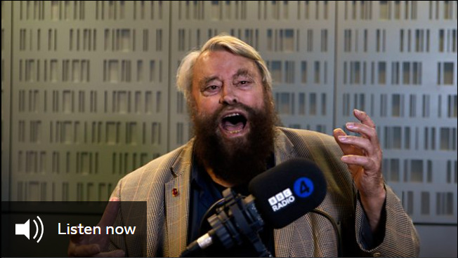 Brian Blessed, a bearded man, stands speaking in front of a microphone branded with the BBC Radio 4 logo. A button reads 'listen now'