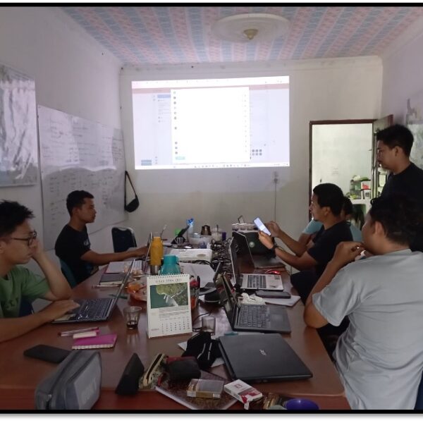 Six people sit around a table with laptops, in a training workshop