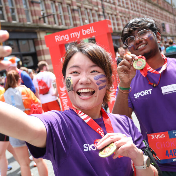Two smiling people take a selfie as they complete the Great Manchester Run, proudly showing their medals